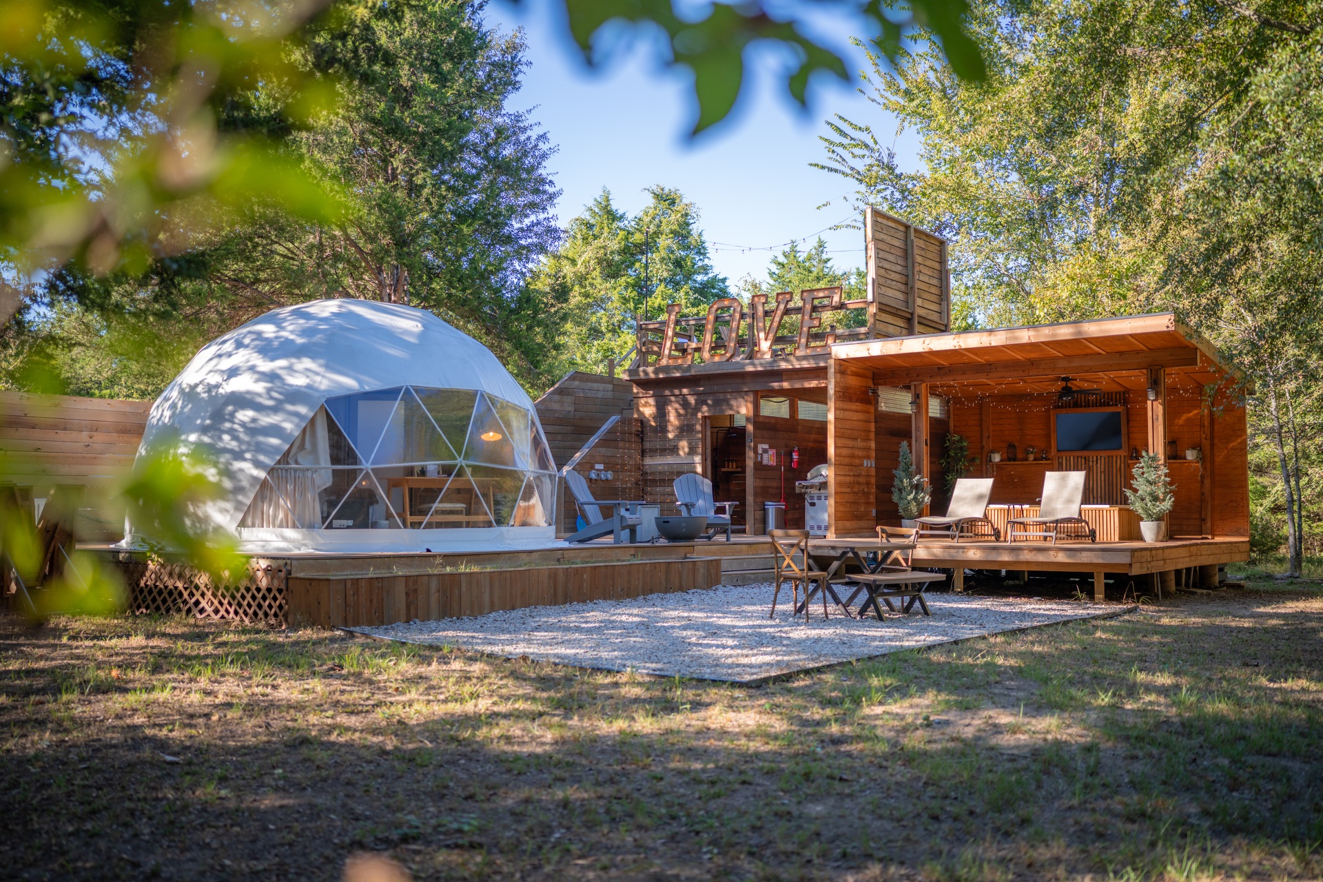 Starlite dome and covered outdoor lounge surrounded by trees